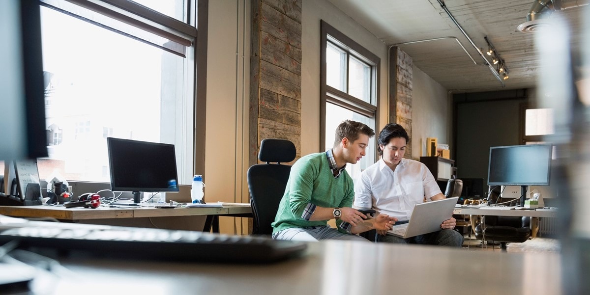 Two businessmen working together on a laptop in the office